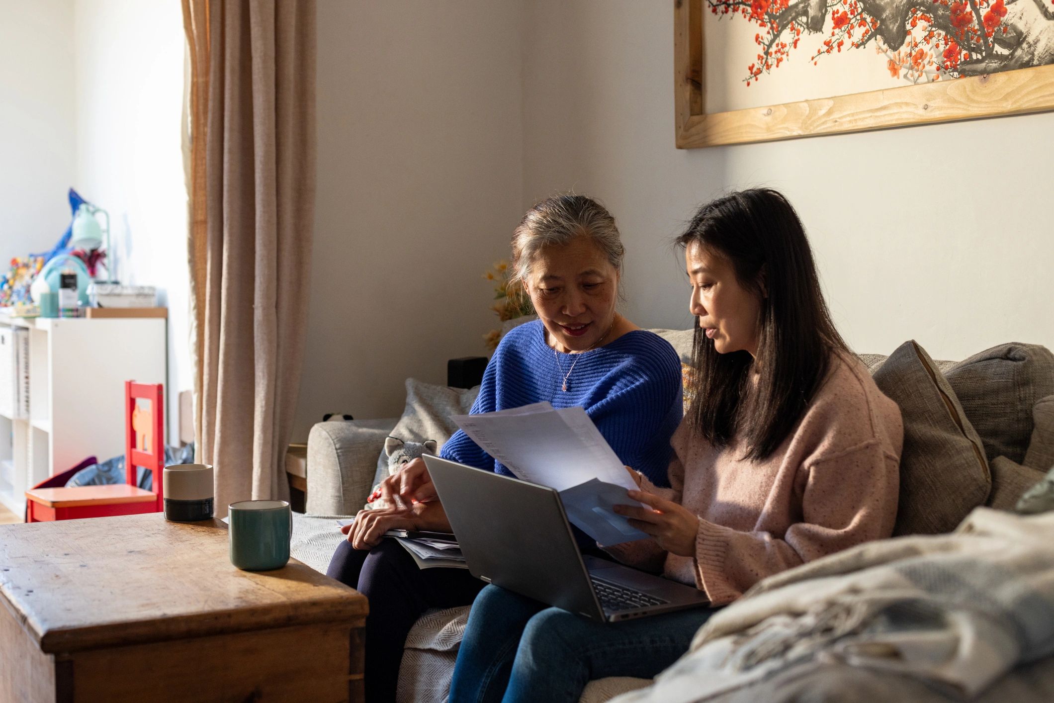 Adult daughter helping her mother use a laptop at home
